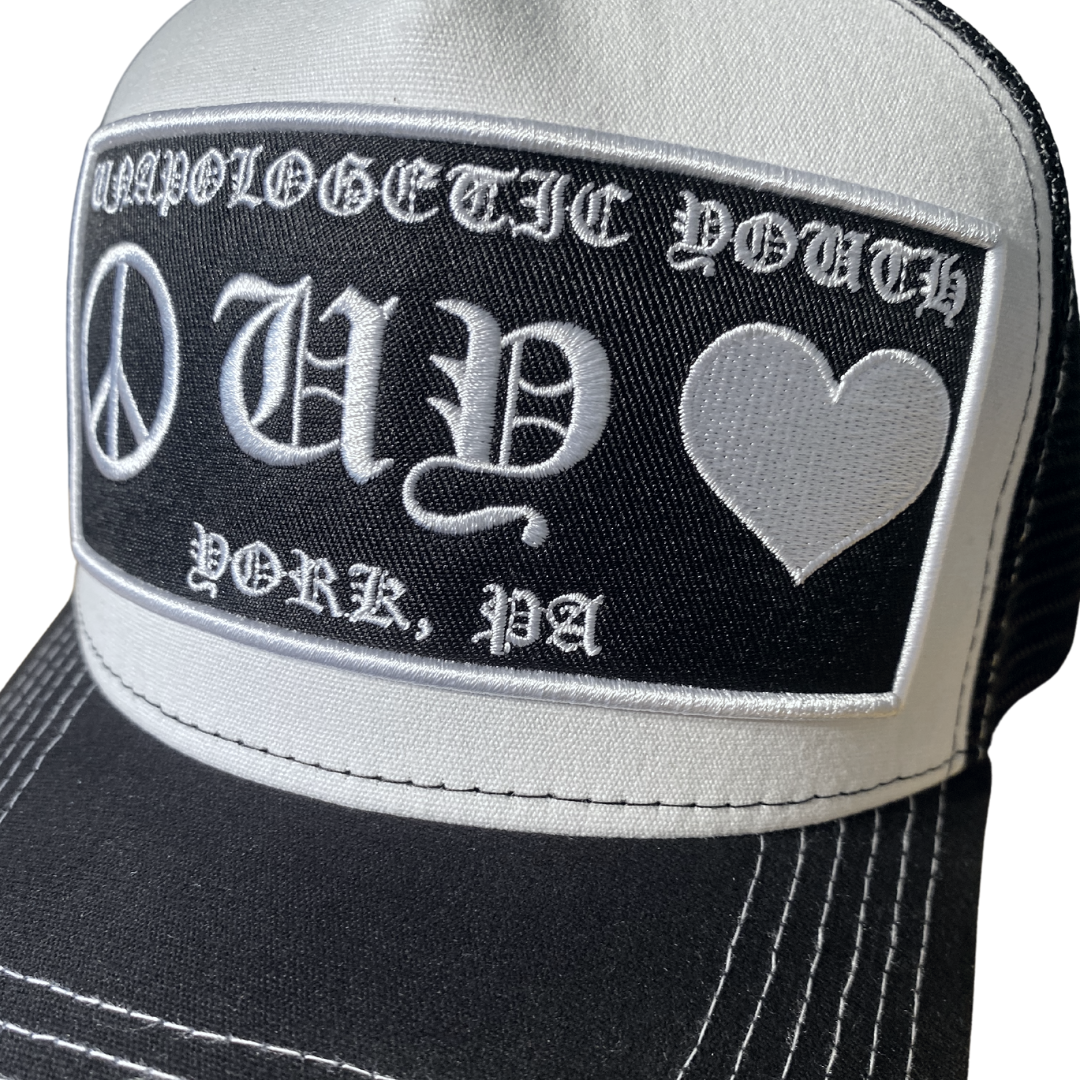 Unapologetic Youth Hearts trucker hat featuring a red heart design on white mesh, adjustable snapback closure.