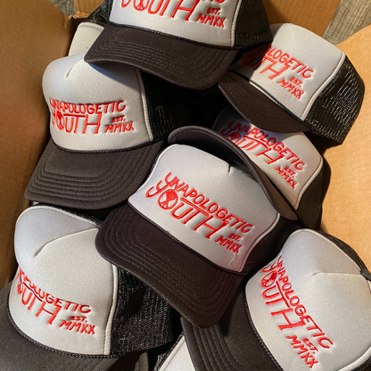 Unapologetic Youth logo trucker hat with adjustable strap and front embroidered logo, casual streetwear accessory.