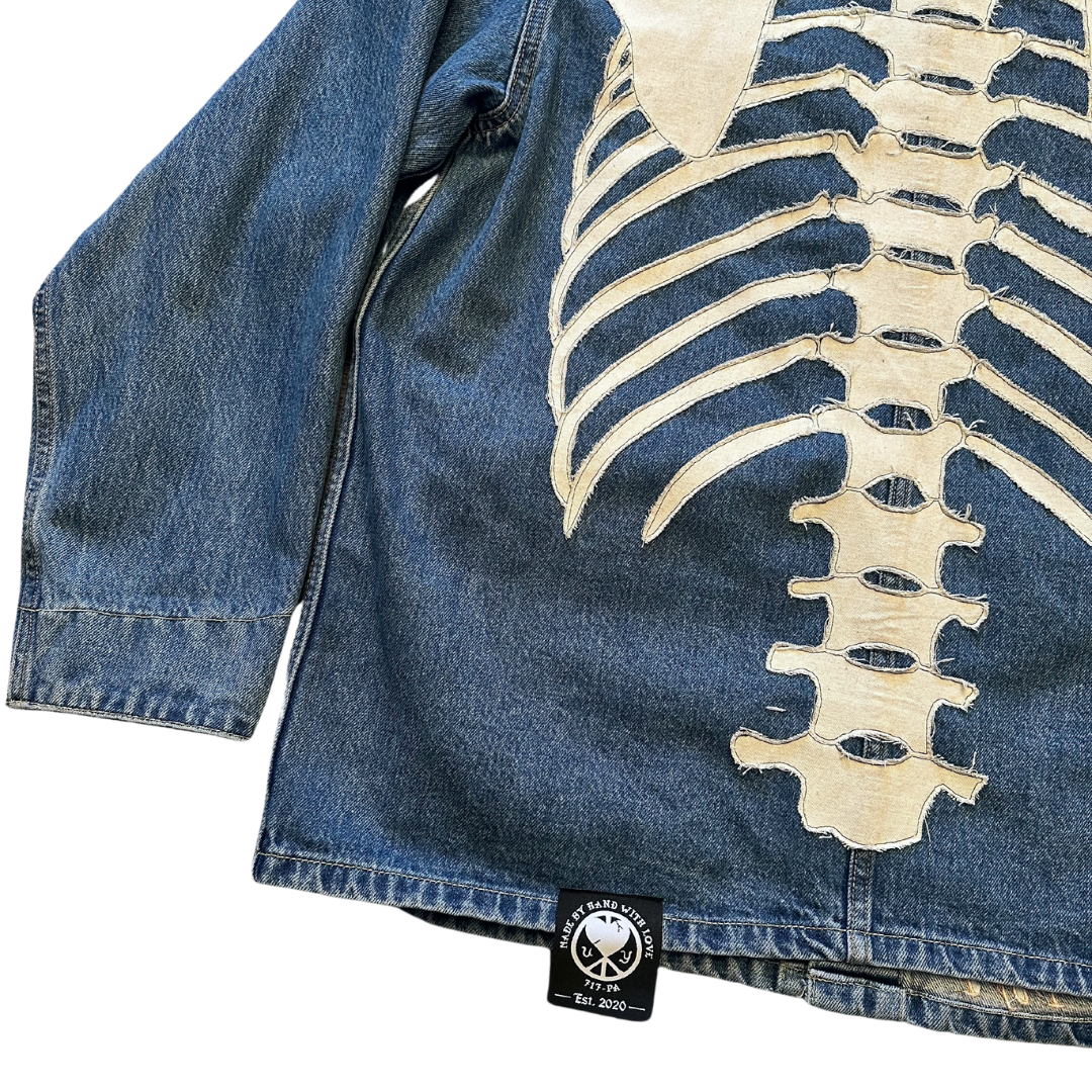 Unapologetic Youth denim jean jacket with bones design, showing front view with classic collar and button closure.