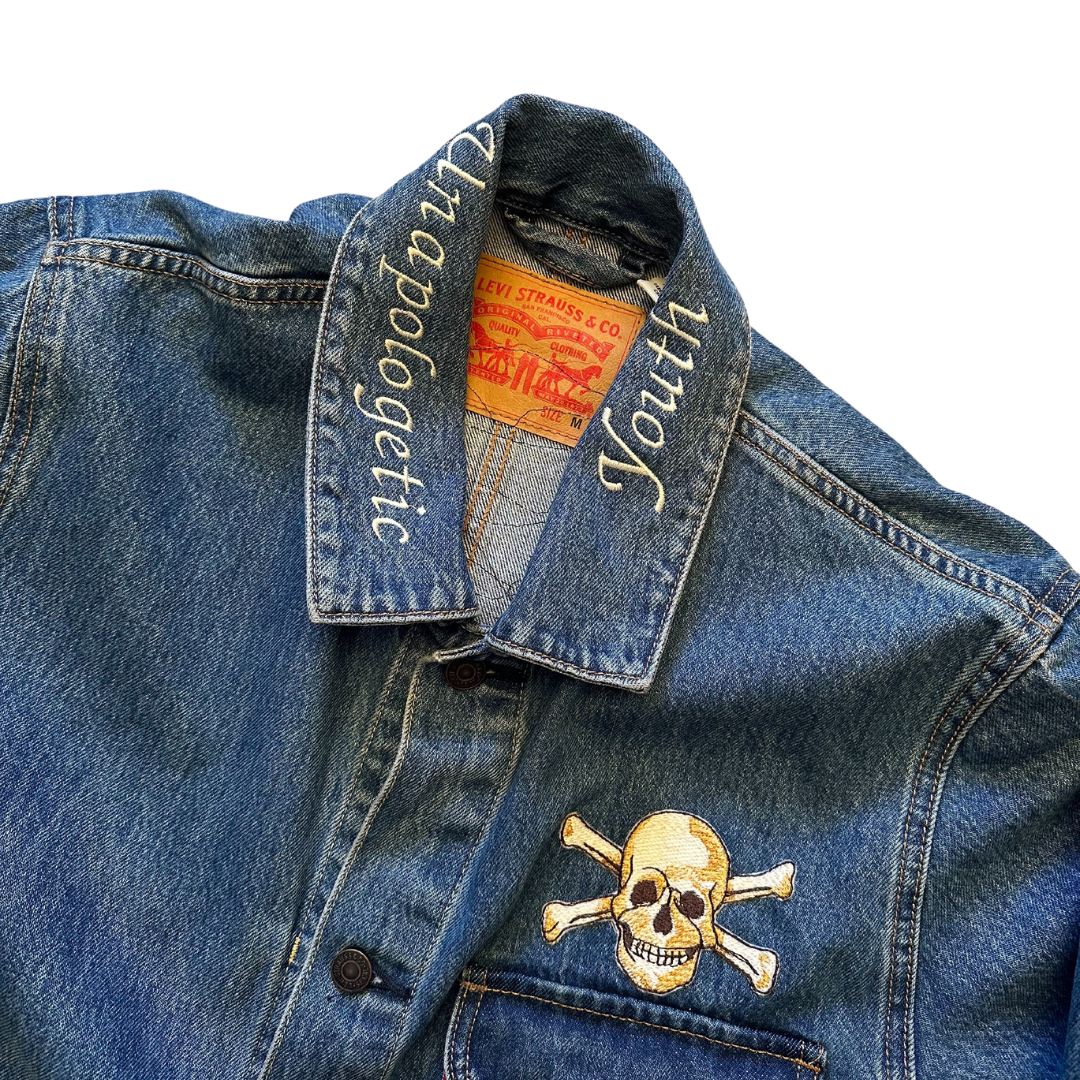 Unapologetic Youth denim jean jacket with bones design, featuring classic fit and distressed details, casual and stylish outerwear.