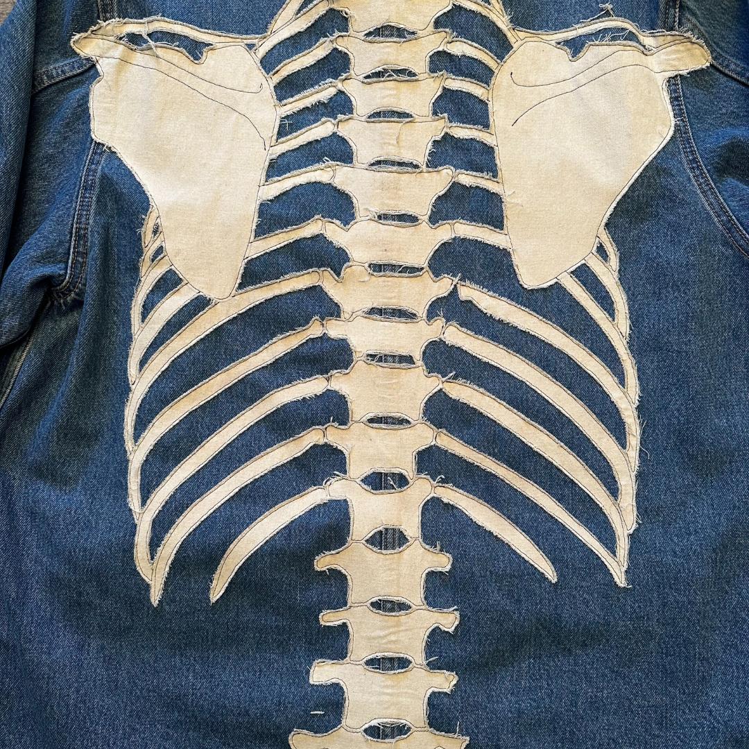 Unapologetic Youth denim jean jacket with bones design, featuring classic fit and button-up front, casual streetwear style.