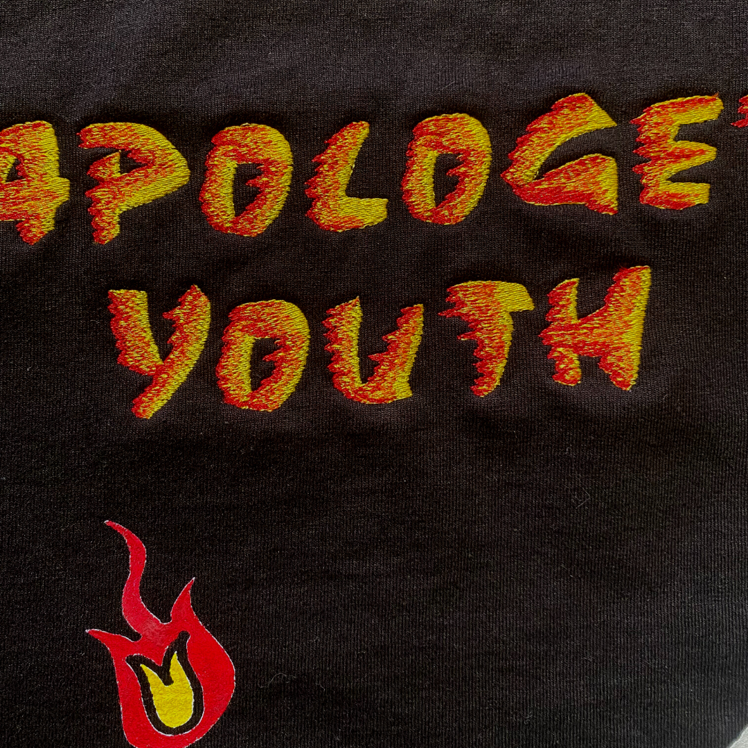 Unapologetic Youth long sleeve shirt with "Ignite The Flame" graphic in bold white letters on black fabric.