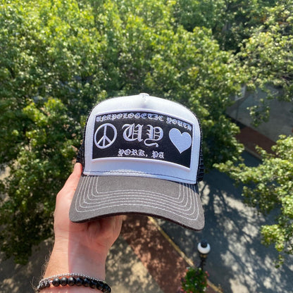 Unapologetic Youth Hearts trucker hat with a colorful heart graphic, adjustable mesh back, and curved brim.
